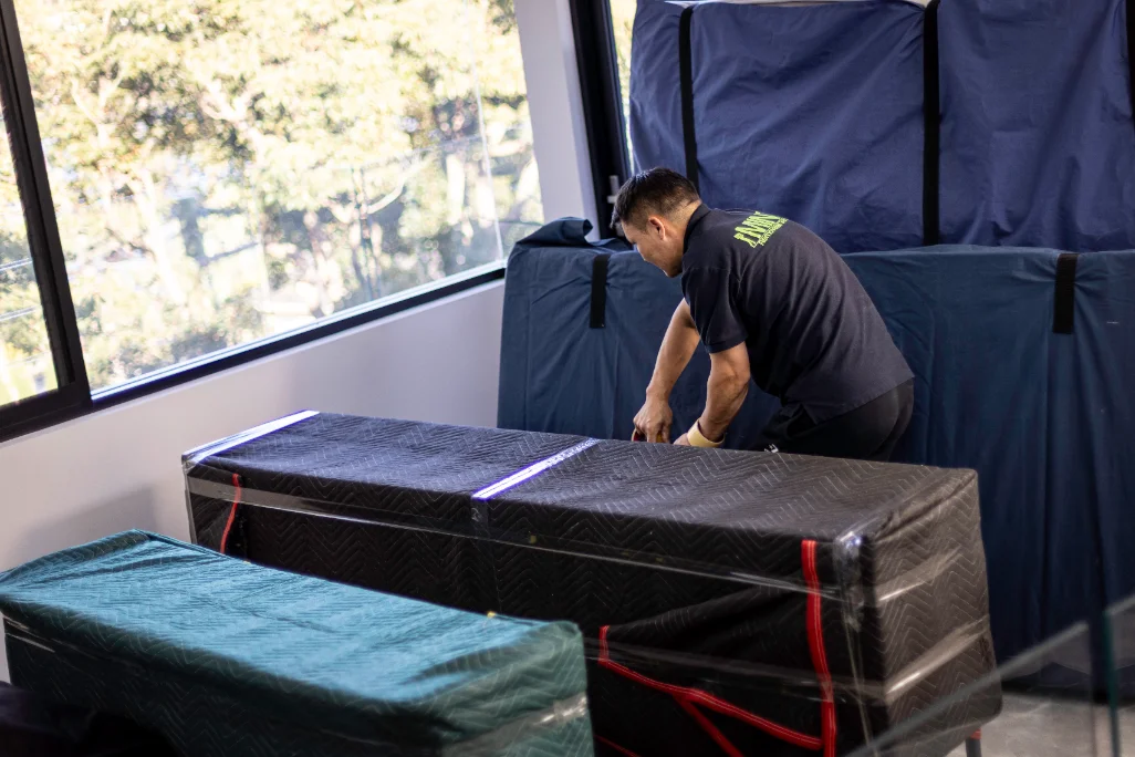 A Mint Removals mover taping protective wrapping around a large flat item