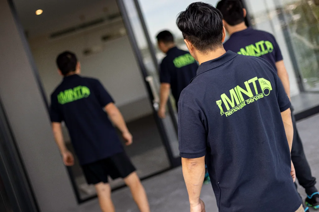 Four Mint Removals crew members in uniform walking through a glass entrance