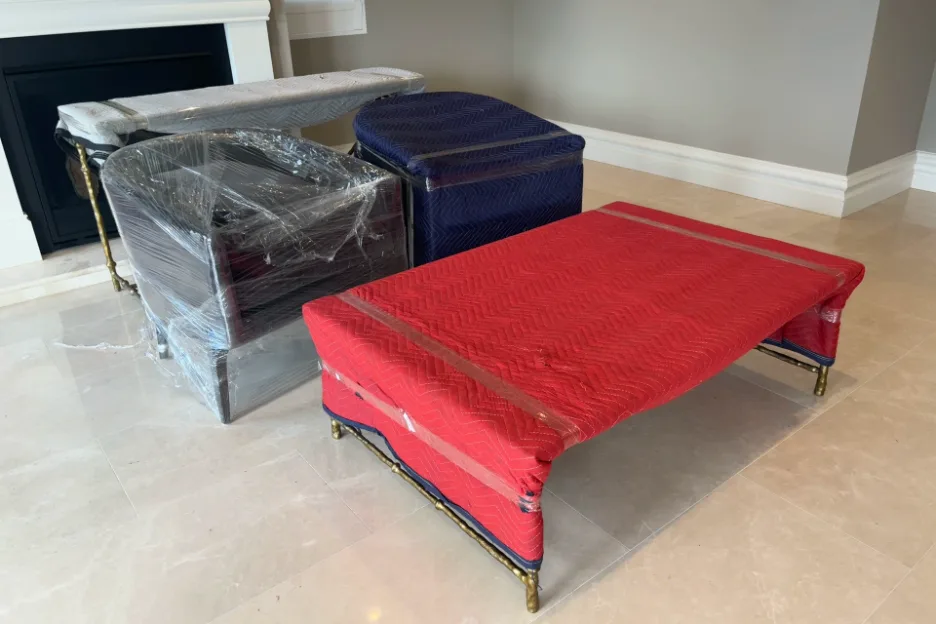 Furniture wrapped in moving blankets and plastic film, grouped together ready to move